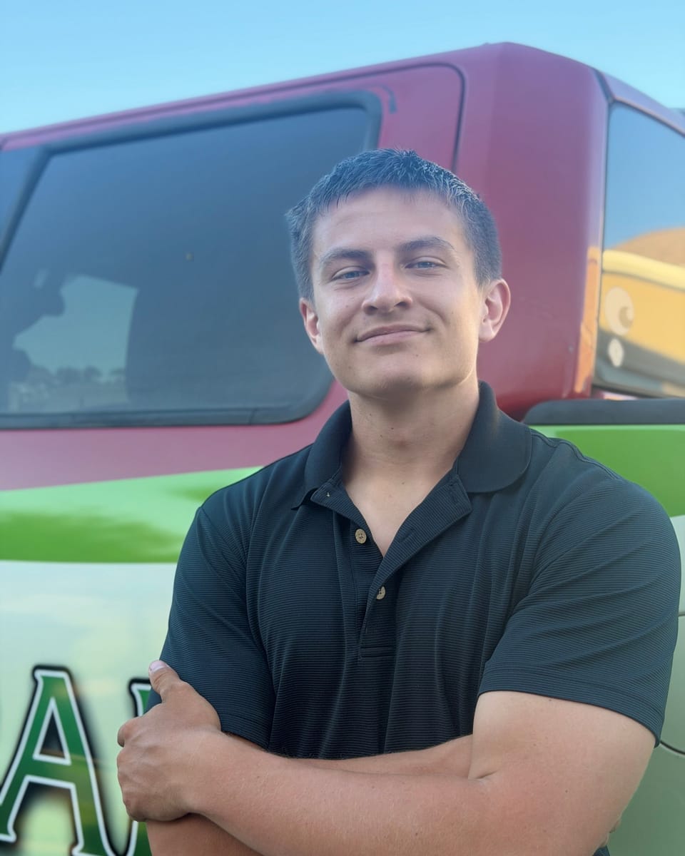 Jake Stoodt, owner of Emerald Solutions, in a black polo in front of his wrapped work truck