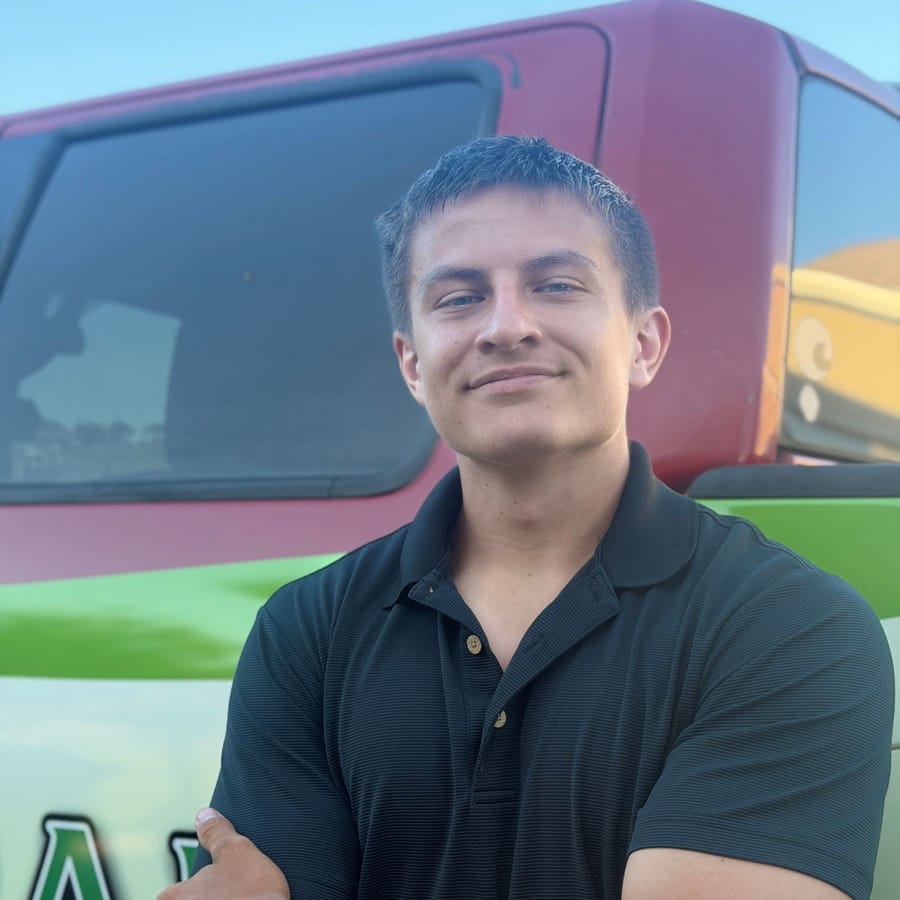Jake Stoodt, owner of Emerald Solutions, arms folded in front of his wrapped work truck